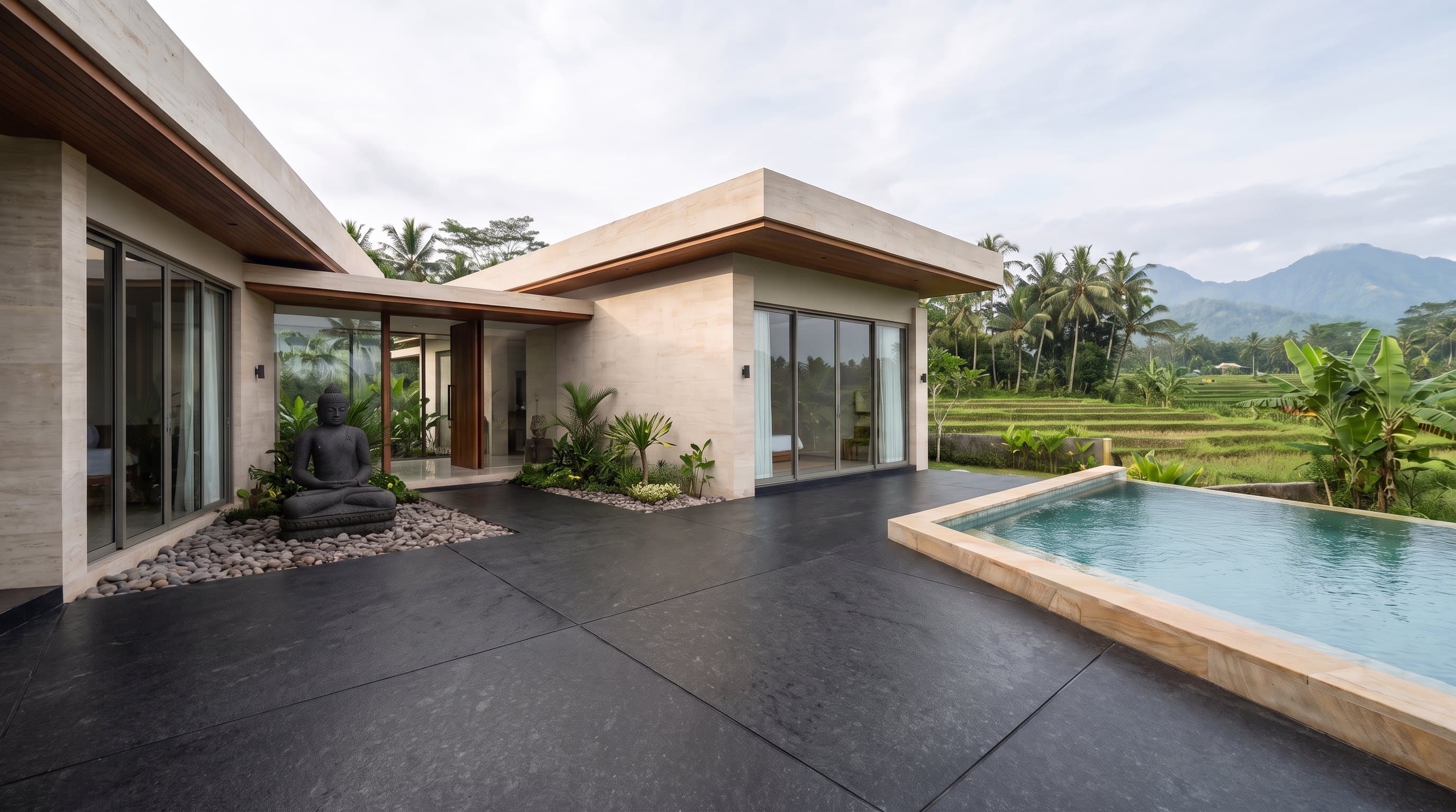 A travertine villa in Bali, a black granite arrival court in the foreground and rice terraces beyond