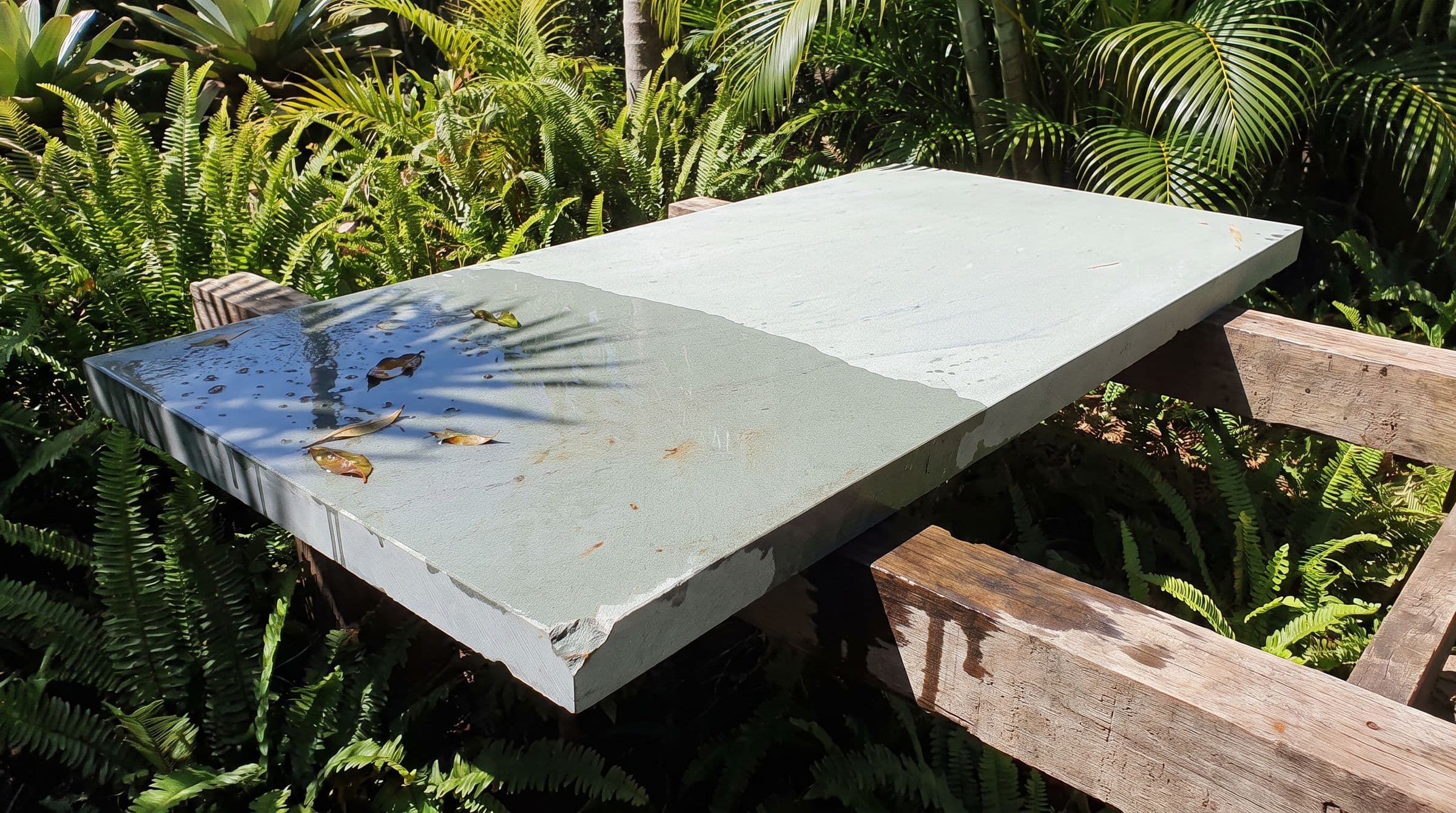 A quartzite slab, half wet after rain, in a garden